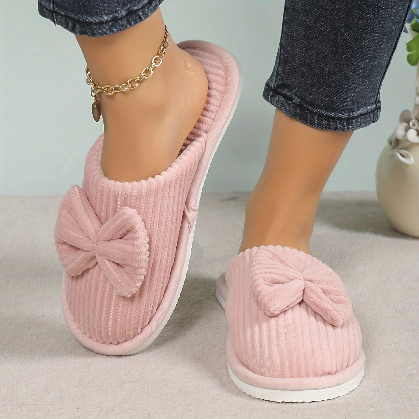 Women's slip-on winter slippers with cozy lining, soft textured surface, and charming bow detail