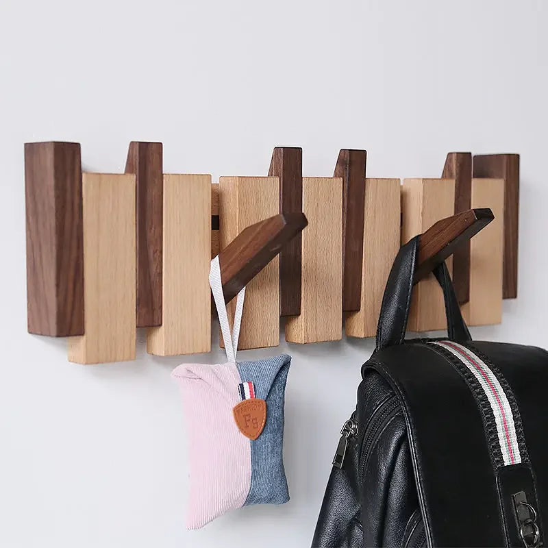 Wall-mounted minimalist wooden coat rack in natural walnut finish with sculptural hooks for entryway
