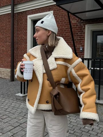 Women's brown shearling jacket with plush lining, modern fitted cut, and luxurious cold-weather warmth