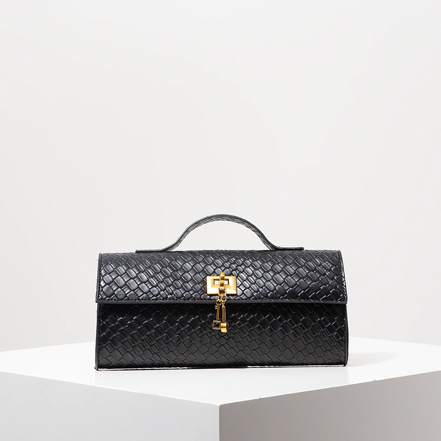 Venezia handwoven vegan leather baguette clutch with gold lock hardware, compact woven texture
