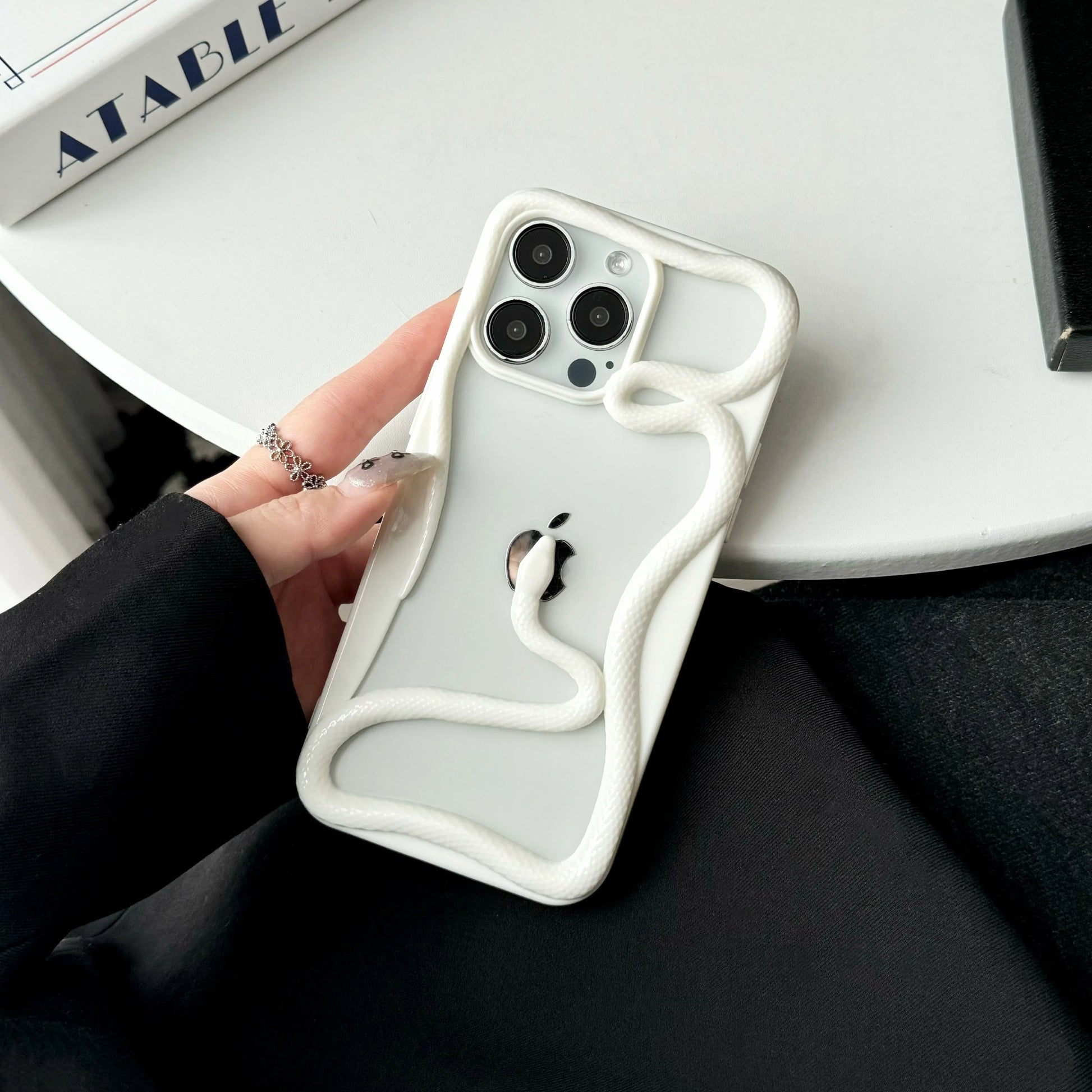 Black iPhone case featuring 3D coiled serpent around Apple logo, garden-inspired bold protective design