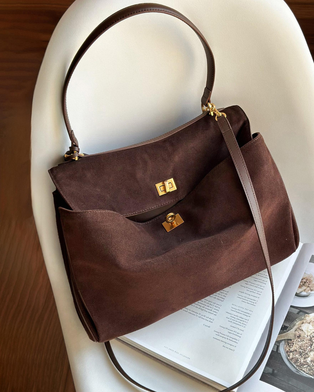 Vintage luxe tan suede top-handle bag with curved flap and gold accents for everyday elegance