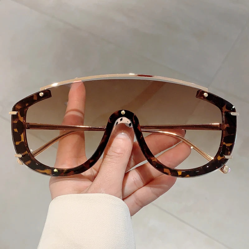 Eclipse oversized visor shield sunglasses with gold-tone accents, avant-garde statement shades for bold fashionistas