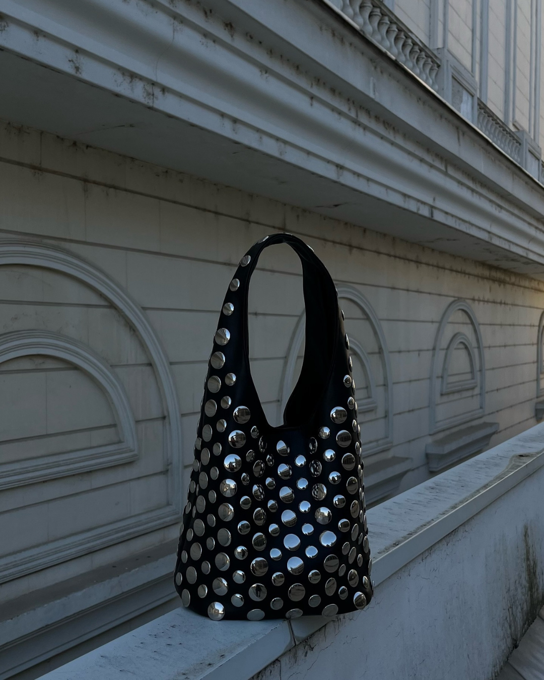 Vienna studded rivet shoulder bag in sleek black with bold hardware embellishment and slouchy silhouette