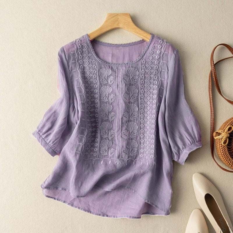 Women's linen blouse with stitched florals, lightweight breathable fabric, and curved dipped hem