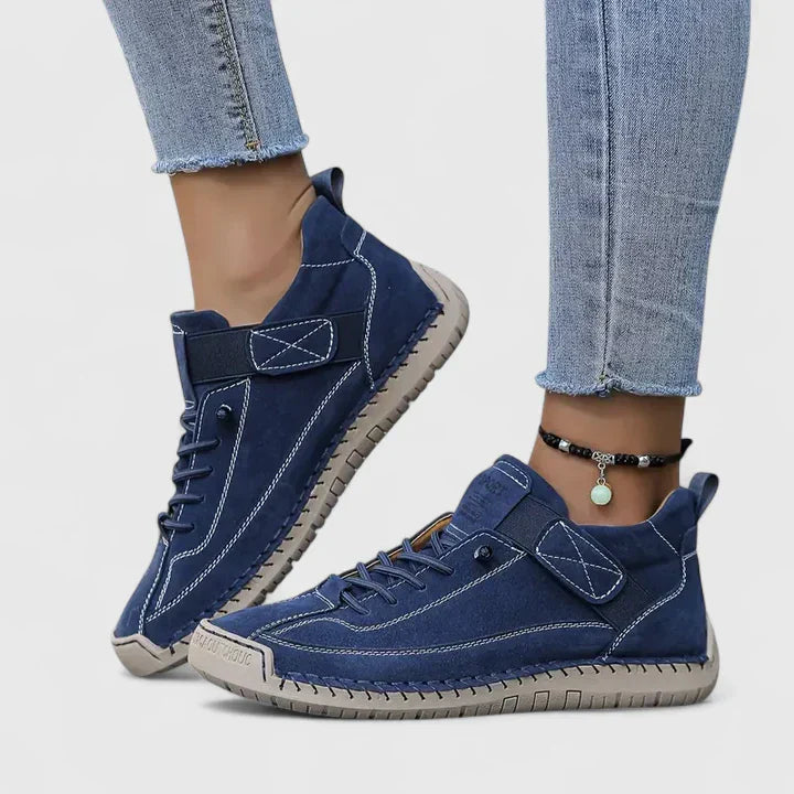 White high-top sneakers with stitched panels, lace-up front, adjustable strap, and structured urban silhouette