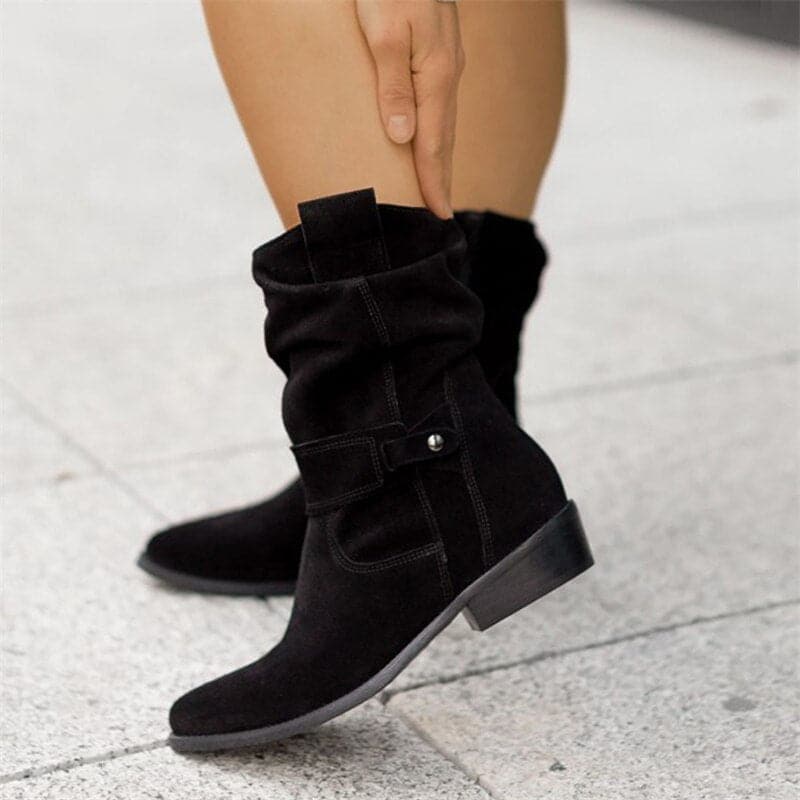 Women's black slouchy mid-calf boots with pointed toe, buckle strap detail, and flat sole