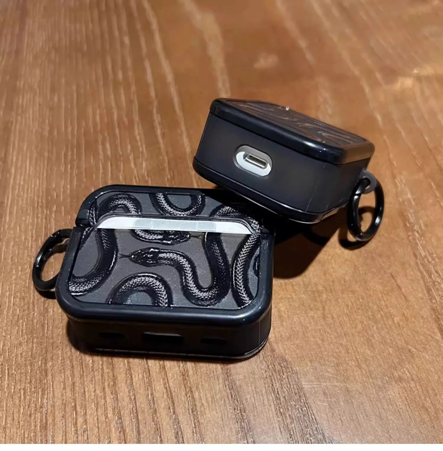Matte black silicone AirPods case with serpent motif, shock-absorbent grip for active use