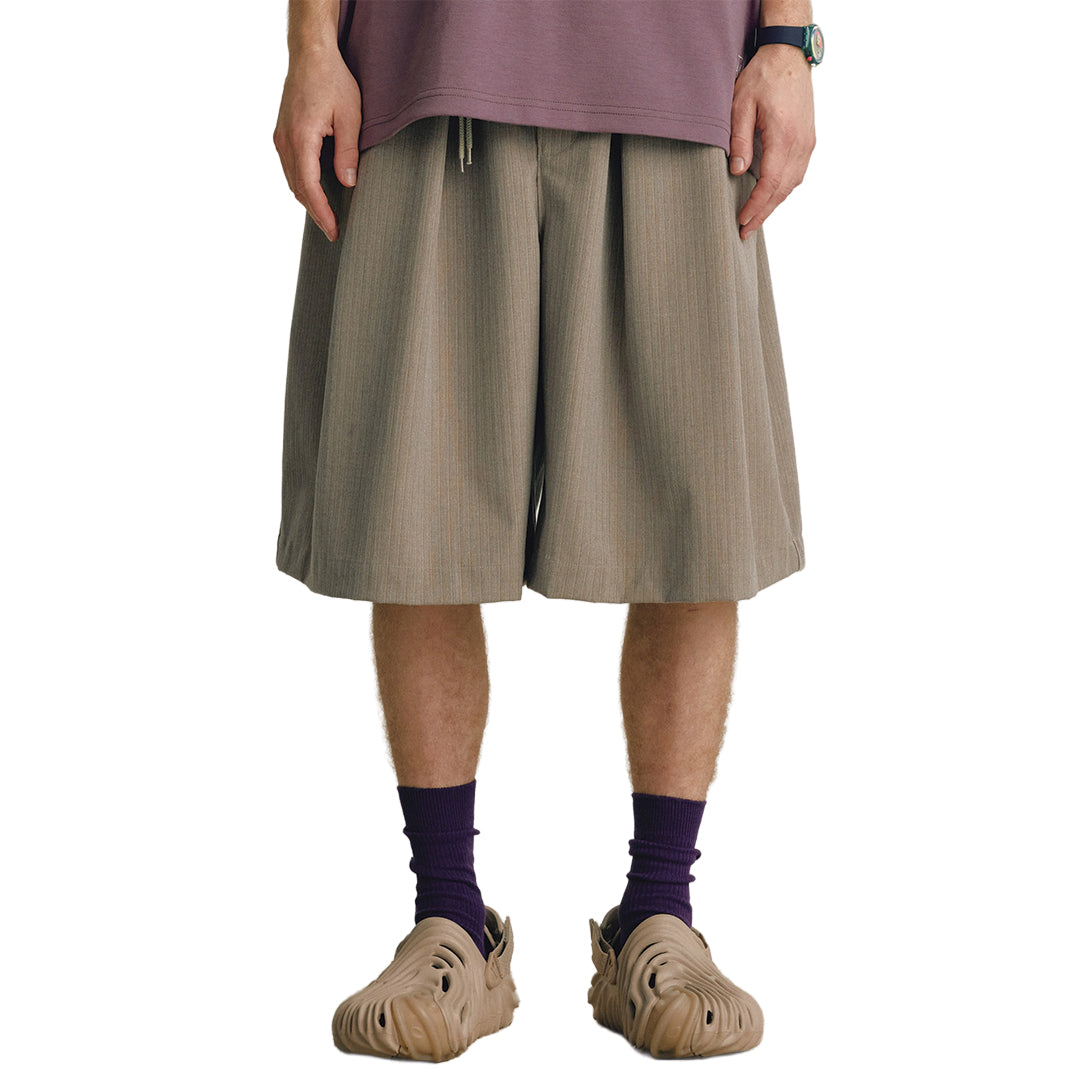 Men's wide-leg calf-length trousers with fluid draped pleats, elastic waist, and drawstring in monochrome