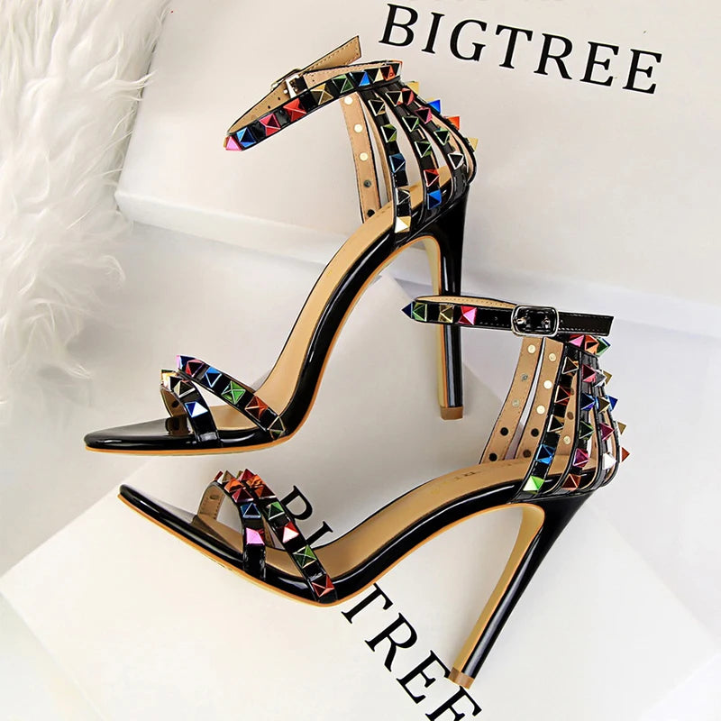 Metallic leather stiletto with pyramid studs, triple straps, pointed toe, and sculpted heel for nightlife glam