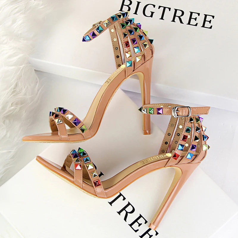 Metallic leather stiletto with pyramid studs, triple straps, pointed toe, and sculpted heel for nightlife glam