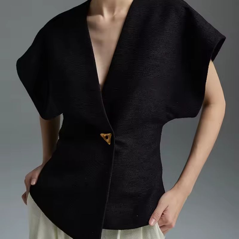 Ivory sculptural wrap top with gold-tone clasp, defined waist, and architectural silhouette for modern women
