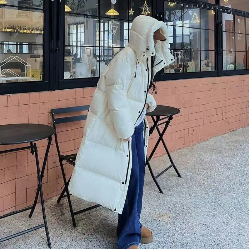 Women's long oversized down jacket with hood, cozy elegant winter style in soft neutral tones