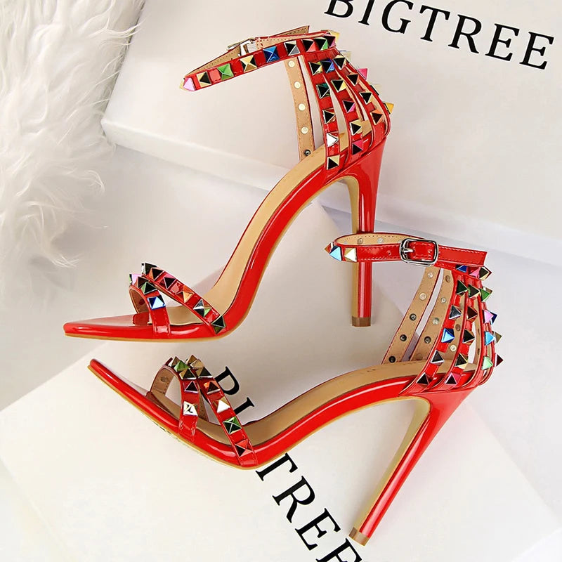 Metallic leather stiletto heels with pyramid studs, triple straps, pointed toe, and sculpted heel for nightlife glam