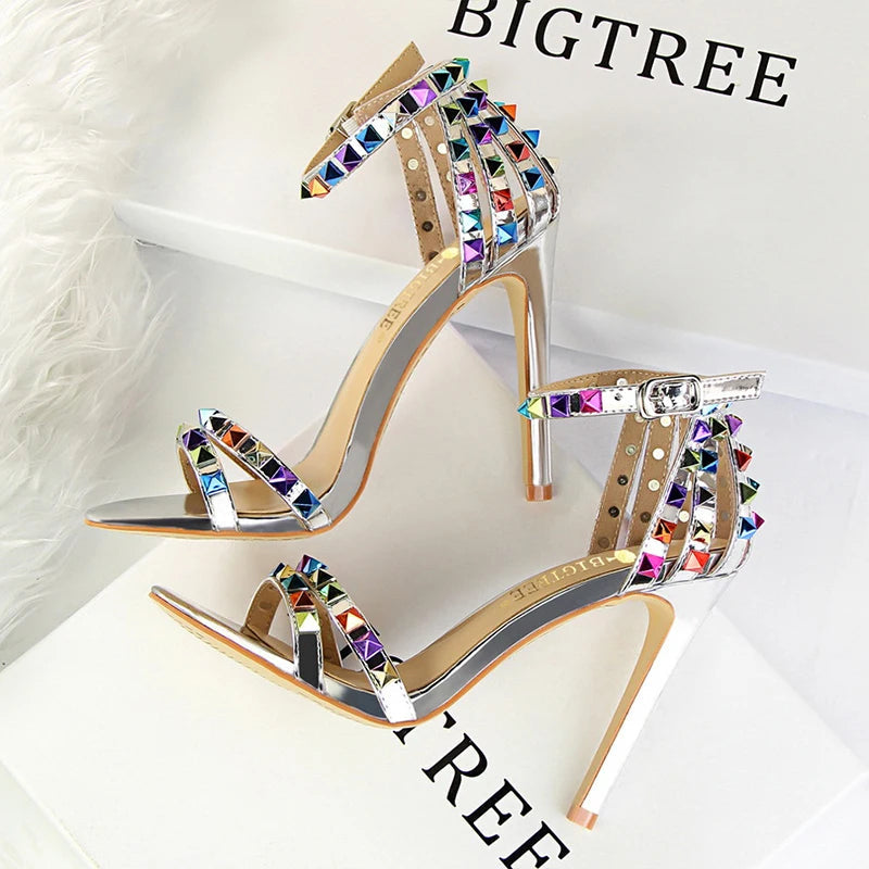 Metallic leather stiletto with pyramid studs, triple straps, pointed toe, and sculpted heel for nightlife glam