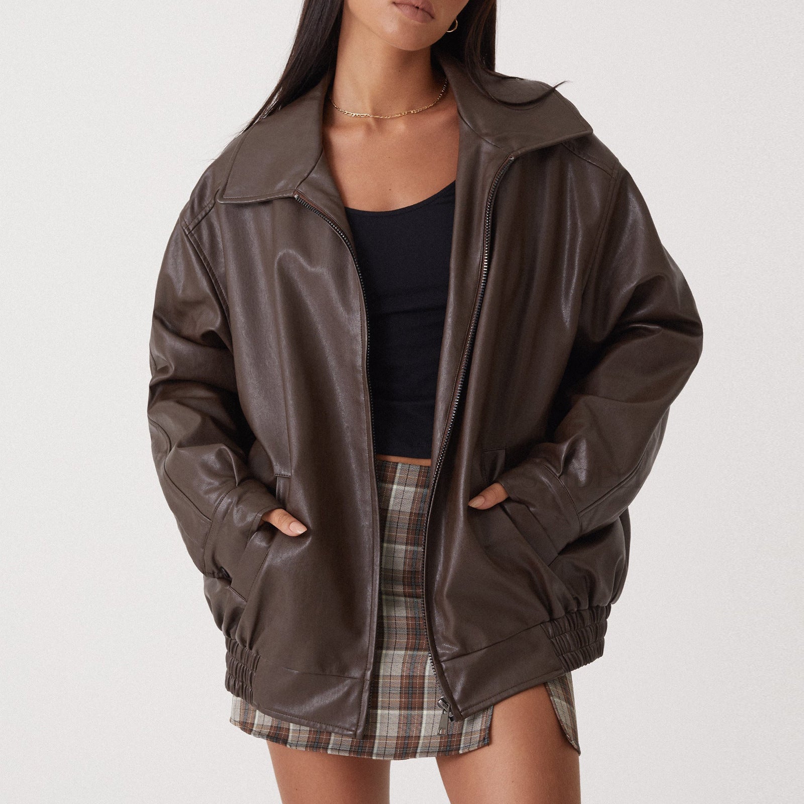 Women's black vegan leather locomotive coat with streamlined silhouette and statement outerwear styling