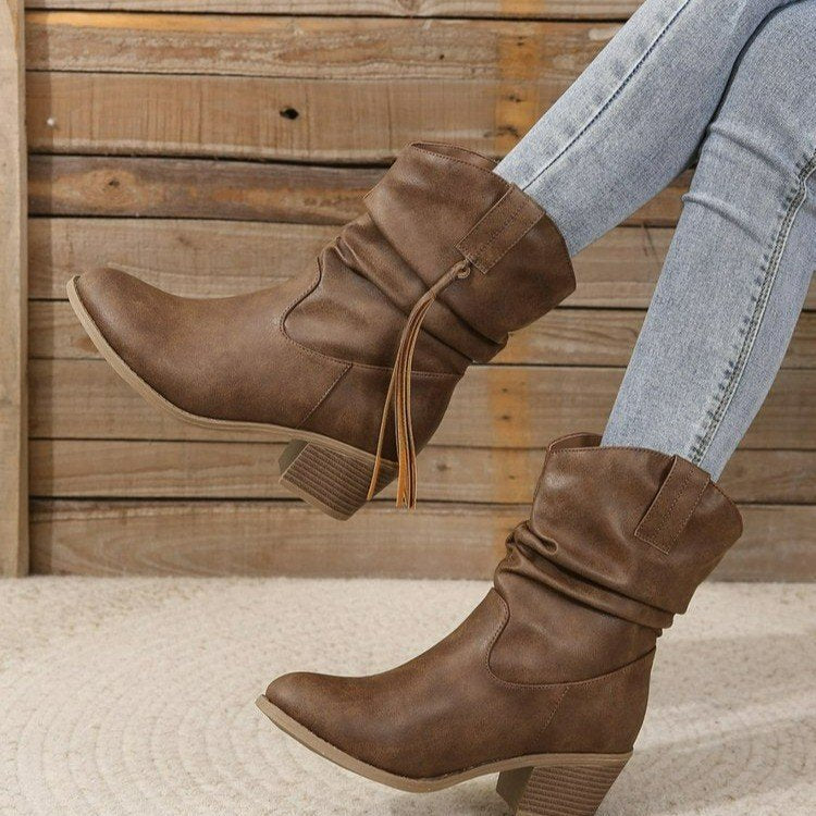 Brown leather western ankle boots with tassel fringe and braided buckle accent for cowboy style