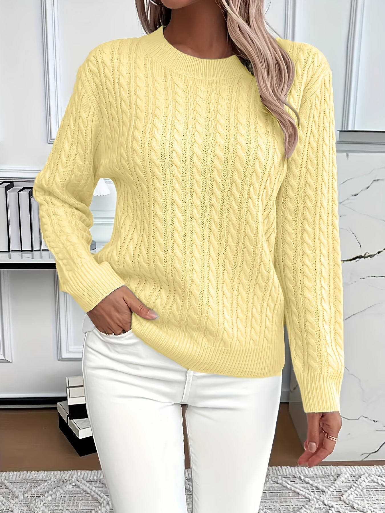 Women's cream cable knit sweater with round neckline, long sleeves, and classic twisted knit texture