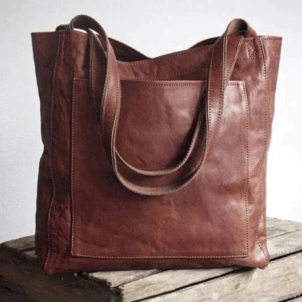 Women's tan faux leather tote bag with snap closure, exterior slip pocket, and dual top handles