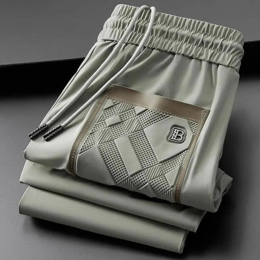 Men's slim-fit silk blend track pants with textured panels, sleek sheen, and refined streetwear style