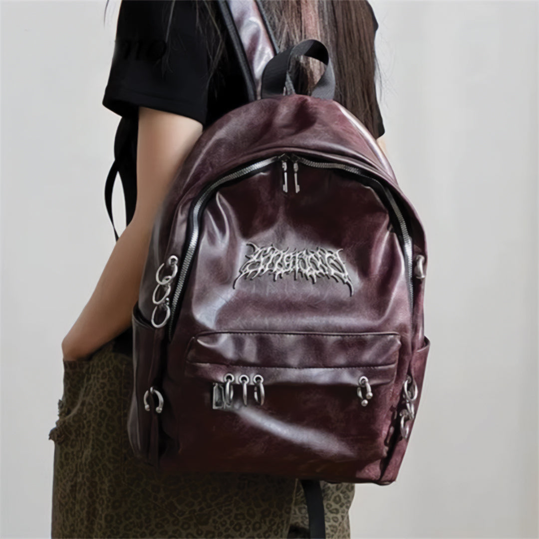 Rebel Chrome vegan leather punk backpack with metal circle accents, secure zippers, and spacious front pouch
