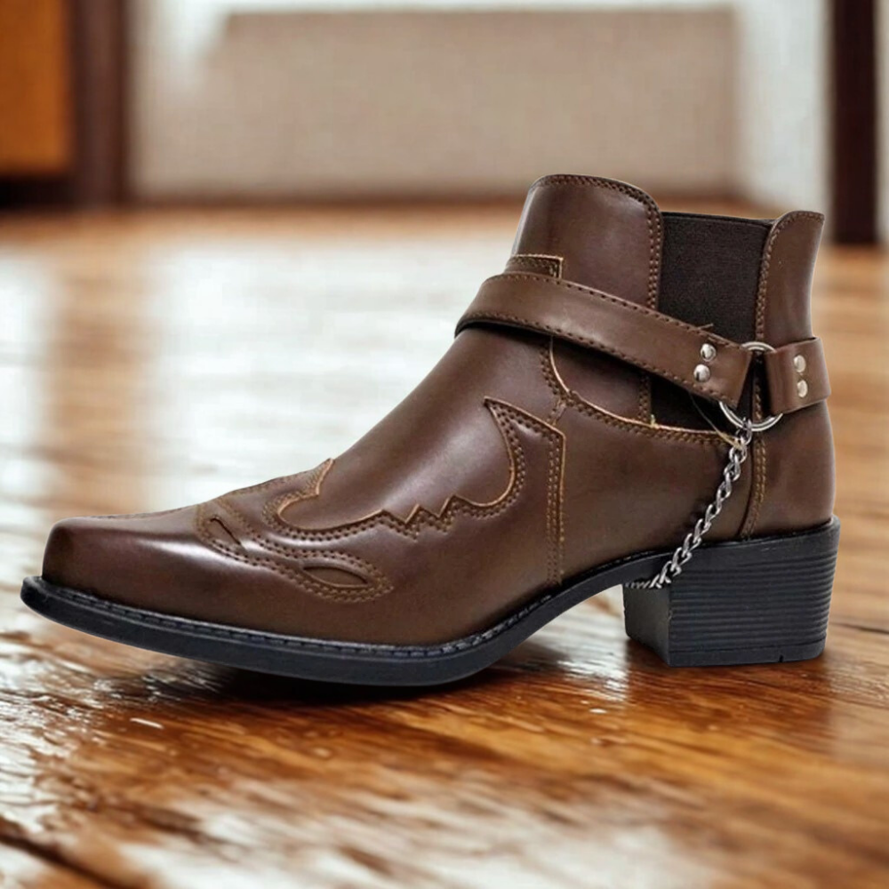 Men's brown faux leather ankle boot with pointed toe, block heel, and buckle chain detail