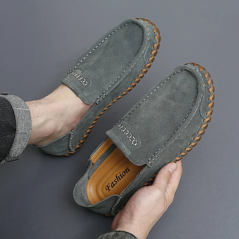 Men's suede loafers in neutral tone, lightweight slip-on style with hand-stitched detailing and textured rubber sole