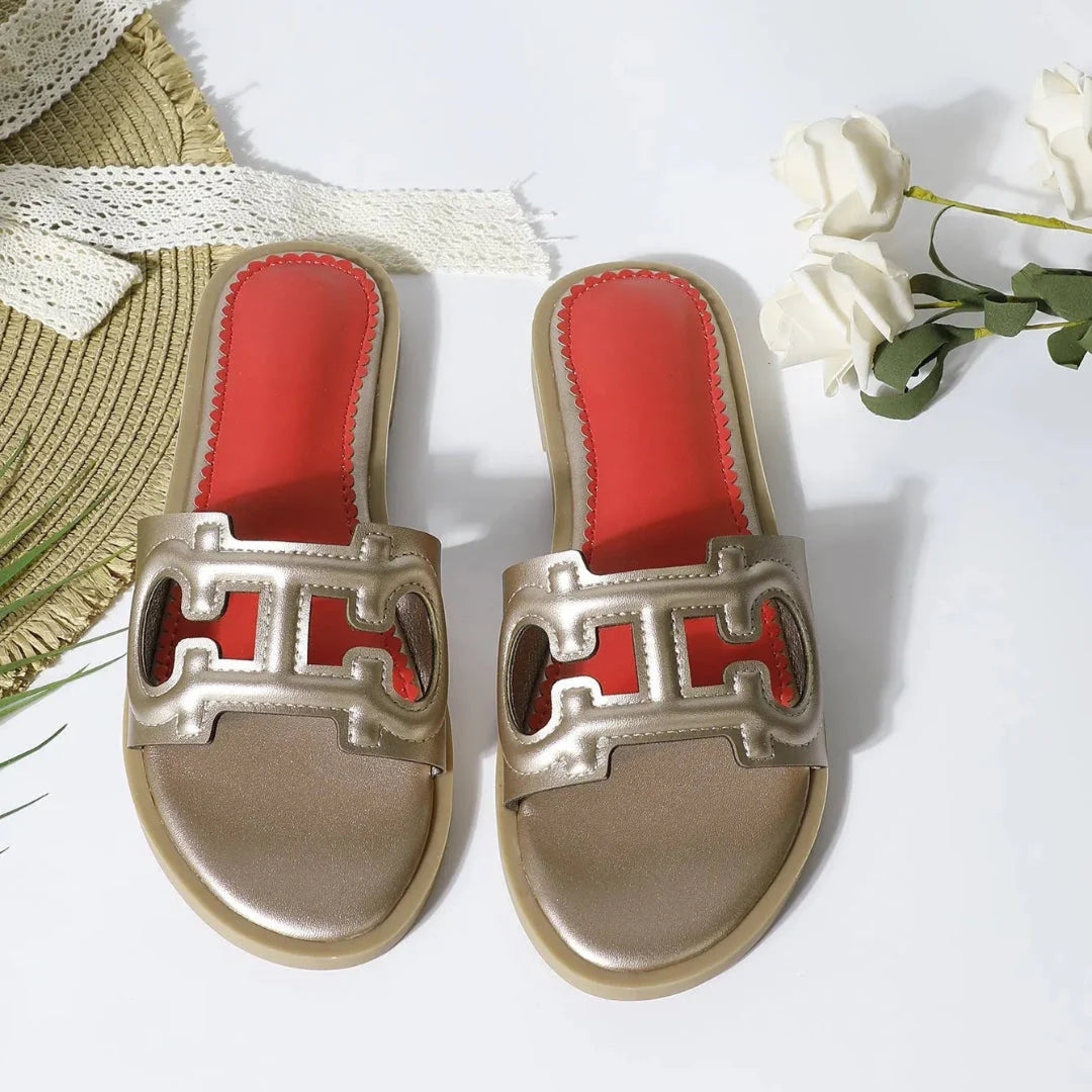 Women's black faux leather cutout slides with bold strap and vibrant red cushioned footbed