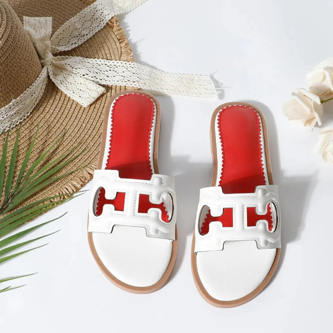 Black faux leather cutout slides with bold strap and vibrant red cushioned footbed for women
