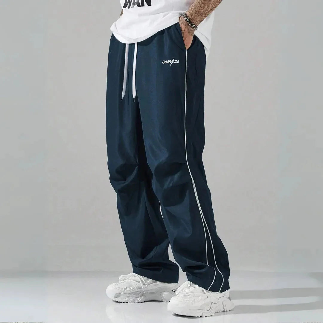 Men's relaxed fit track pants with contrast side piping, drawstring waist, and campus logo
