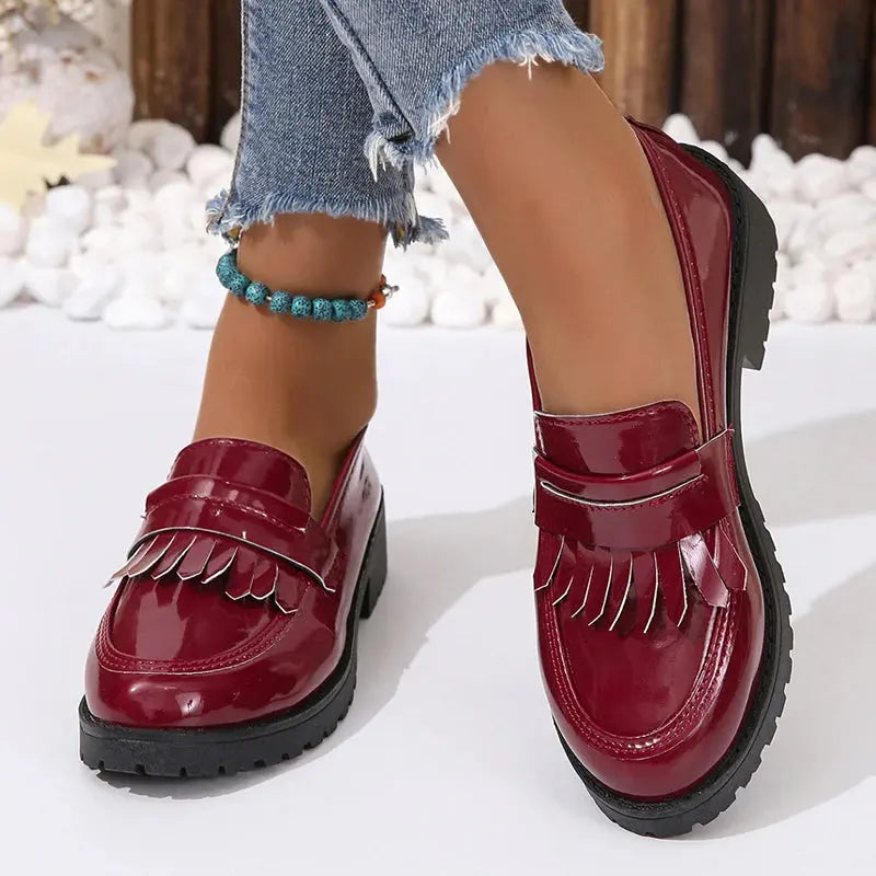 Black chunky women's loafers with fringe tassel detail, patent finish, slip-on retro style