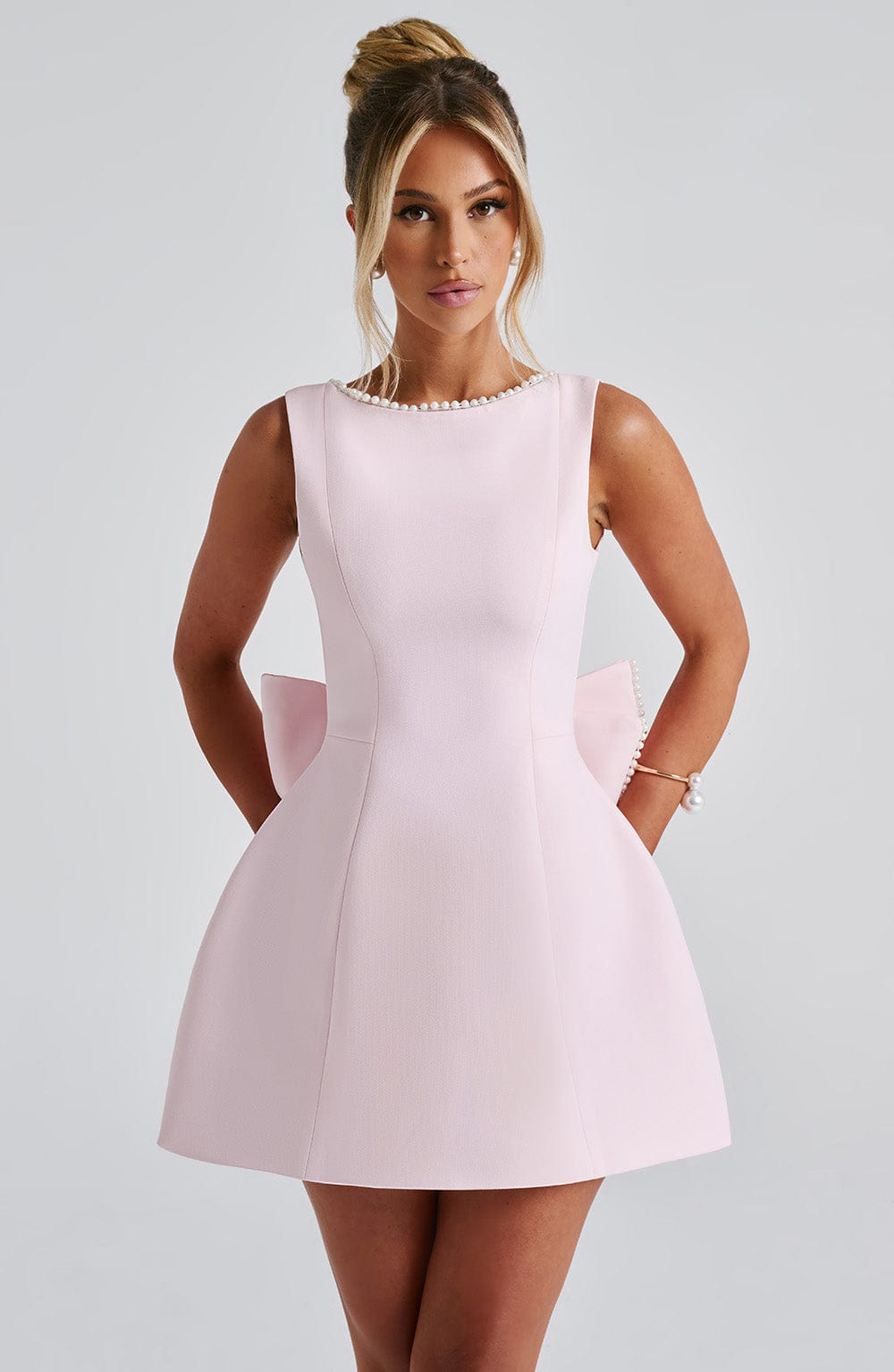 Pink structured mini party dress with pearl trim sweetheart neckline and oversized back bow