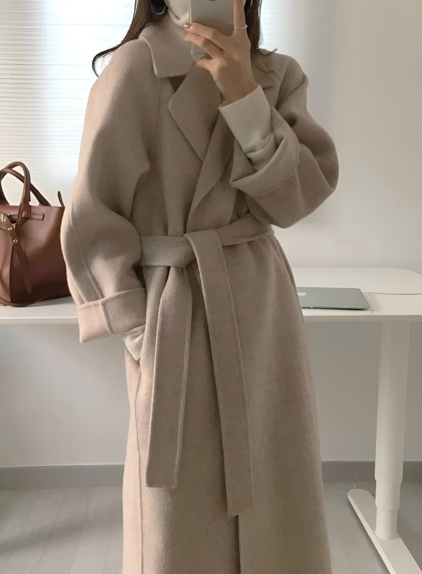 Women's elegant long belted wrap coat in neutral tone, flattering waist-defining silhouette for workwear