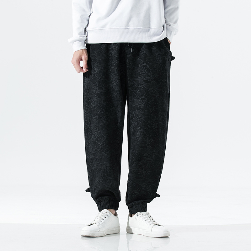 Black tapered joggers with adjustable elastic cuffs, minimalist streetwear silhouette, subtle tonal texture