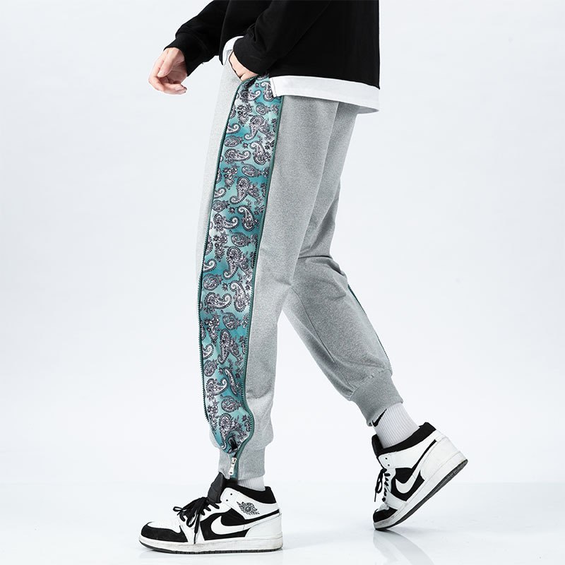 Black tapered joggers with bold paisley panels and ribbed cuffs for streetwear style