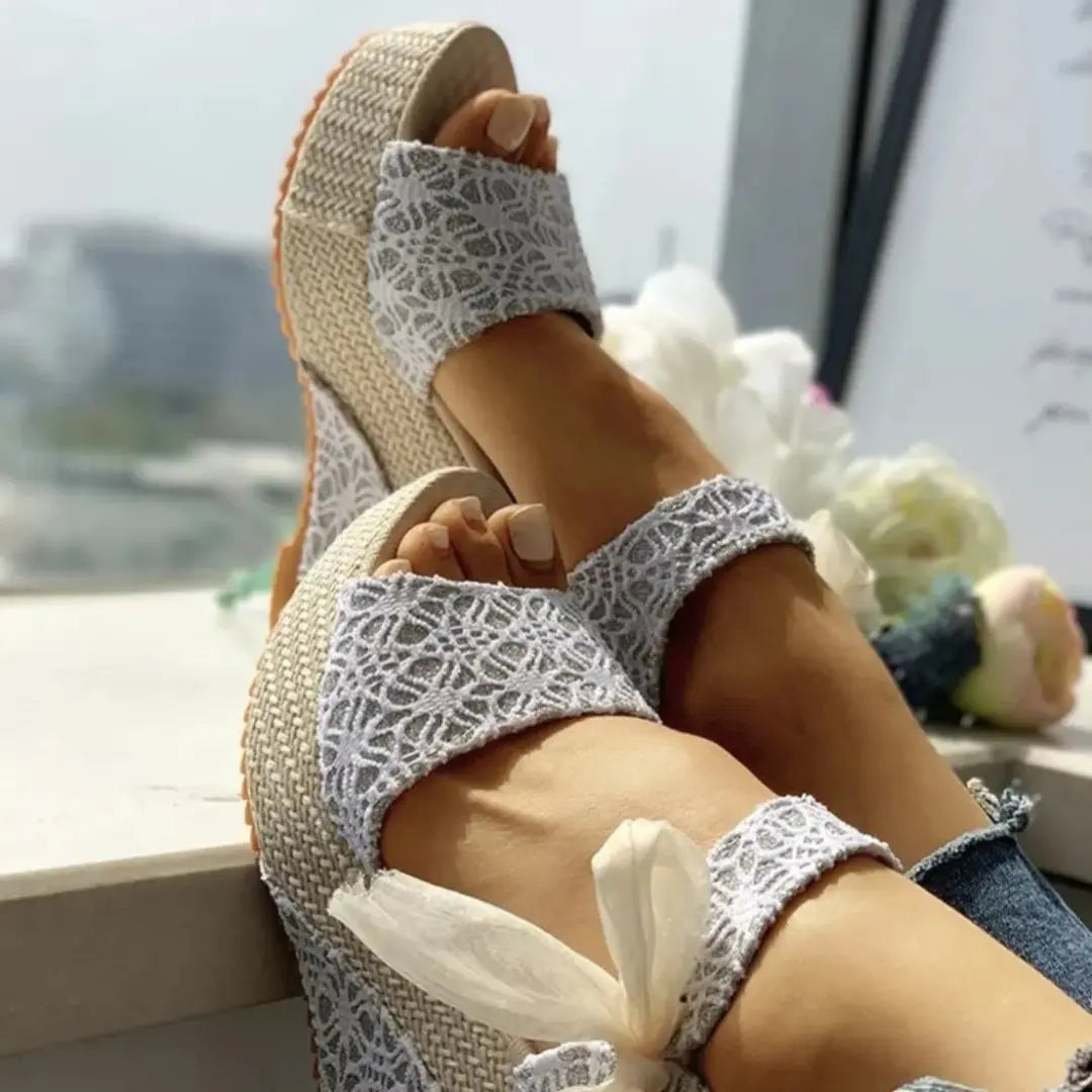 Women's ivory lace bow wedge sandals with ankle tie closure and romantic overlay, perfect for beach weddings