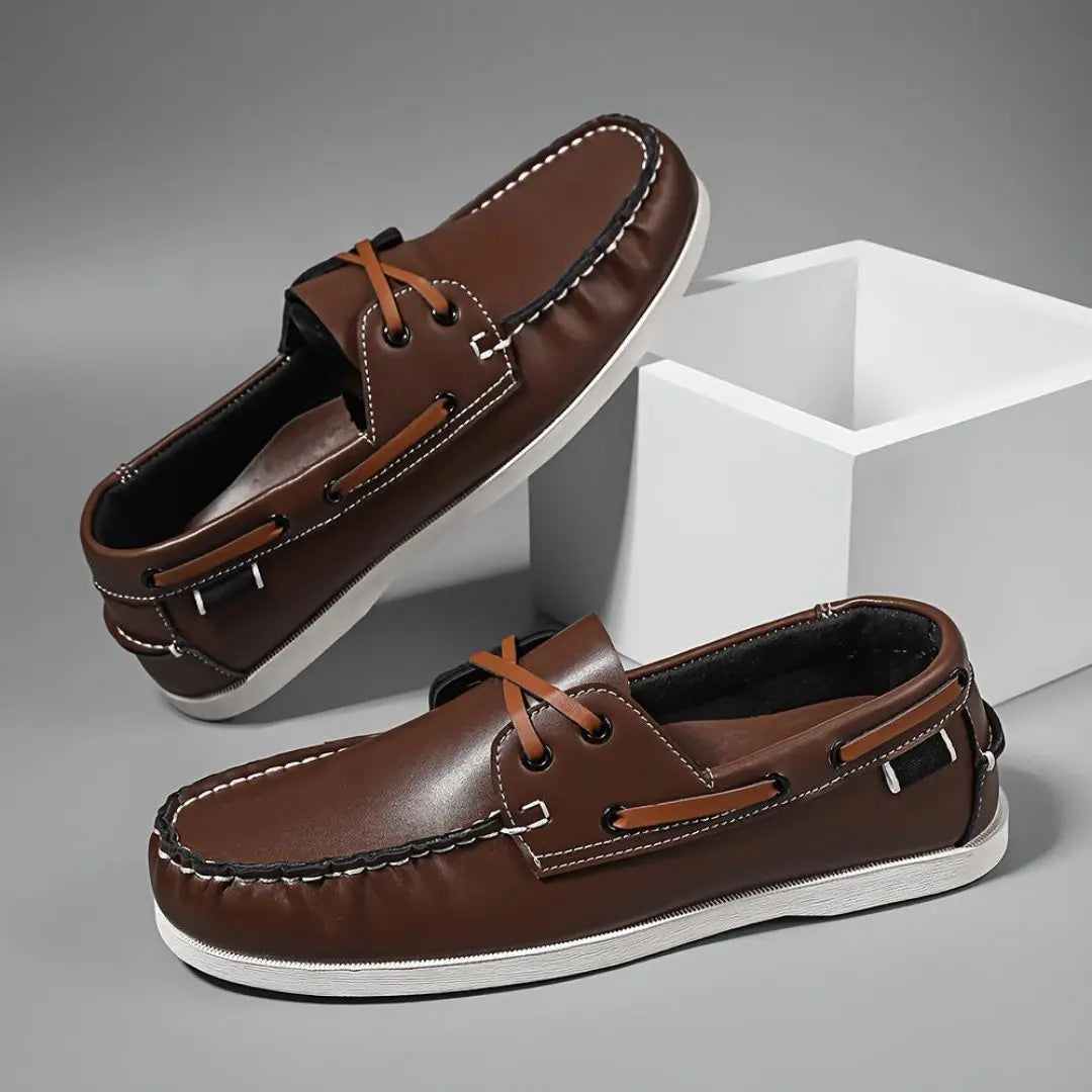 Men's tan leather slip-on boat loafers with classic low-profile silhouette and stitched upper