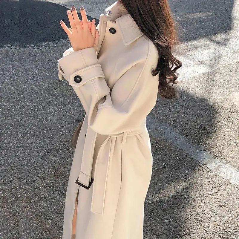 Women's long belted trench coat, classic neutral tone, tailored silhouette with waist-defining belt
