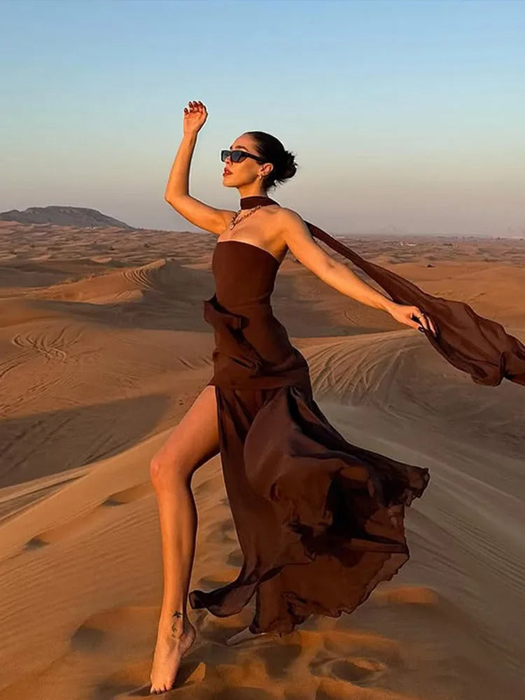 Black strapless evening gown with sculpted bodice, flowing overlay, and dramatic high side slit
