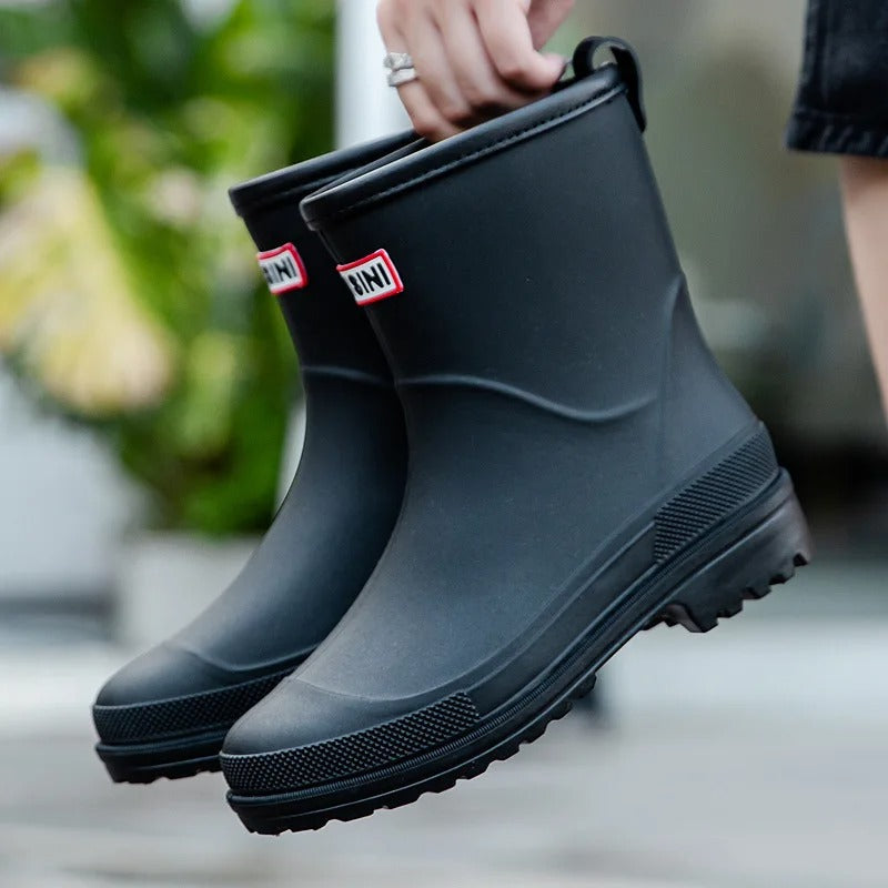Women's mid-cut waterproof PVC rain boots with anti-slip rubber sole, sleek black all-weather style