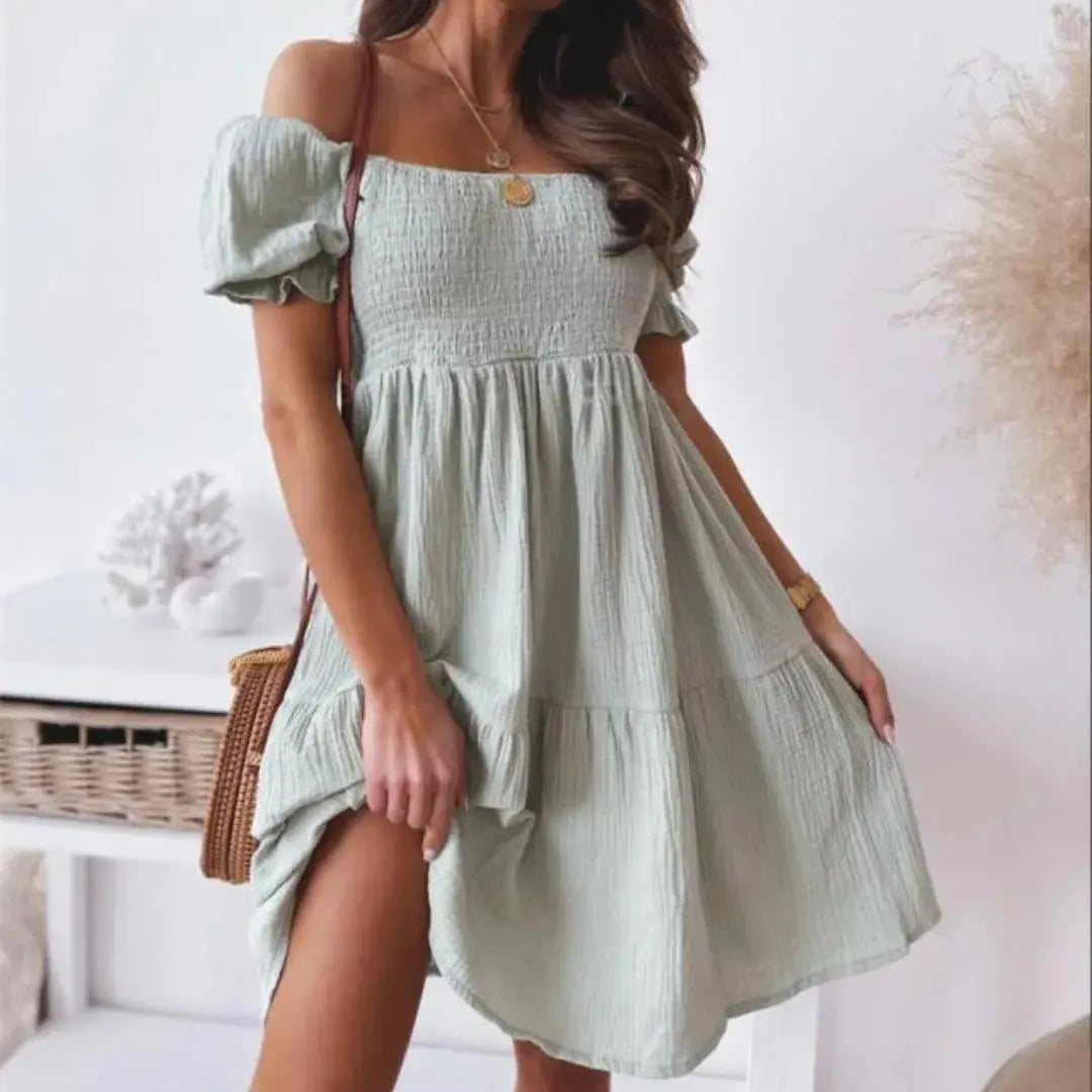 White cotton gauze off-shoulder smocked mini dress with puff sleeves and flared tiered skirt