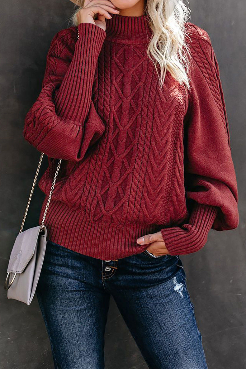 Women's chunky knit sweater in cozy neutral tones with high collar, voluminous sleeves, and hood