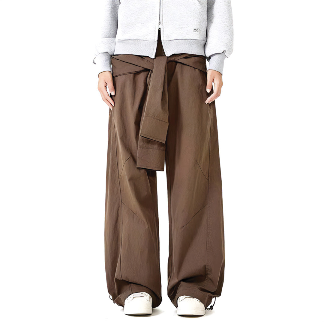 Black minimalist trousers with attached hanging sleeves at waist, loose straight-leg avant-garde design