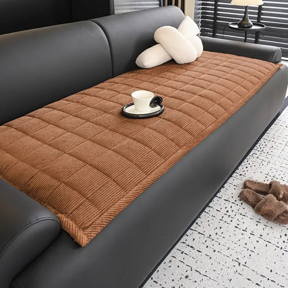 Quilted sofa cover with non-slip backing, pet-friendly protector in neutral tones with textured pattern