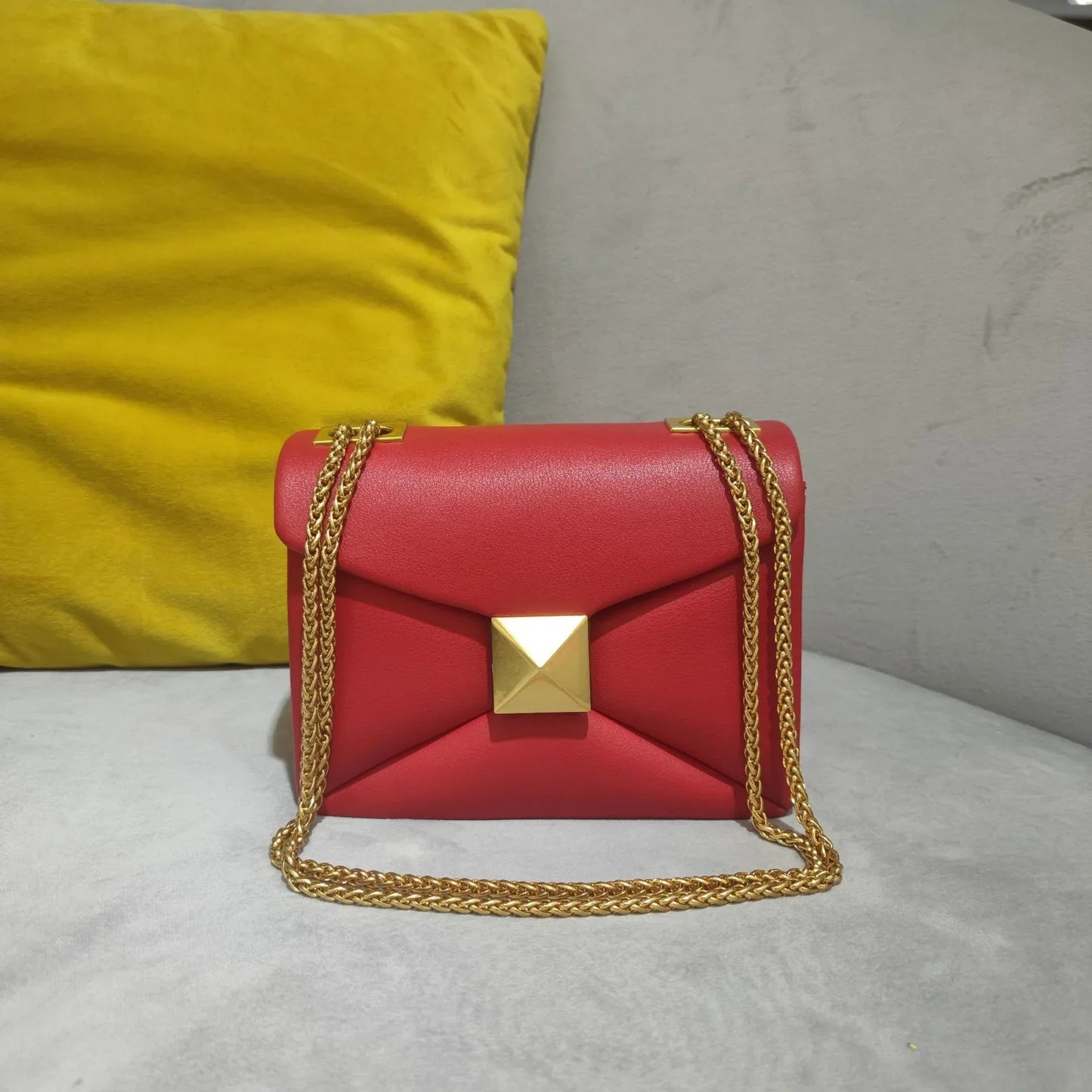 Women's black faux-leather envelope crossbody bag with gold rivet hardware and chain strap