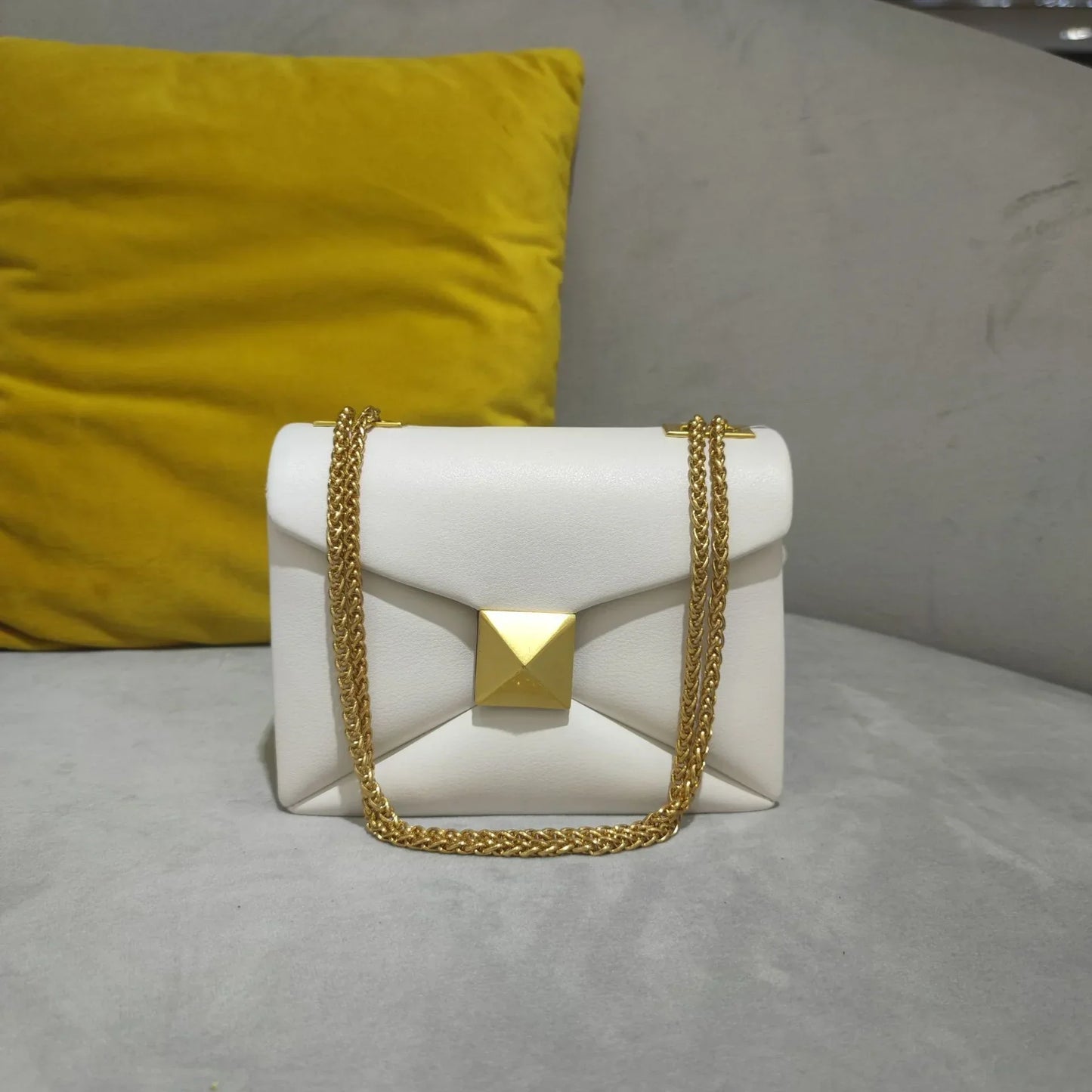 Women's faux leather envelope crossbody bag with rivet hardware detailing and gold chain strap