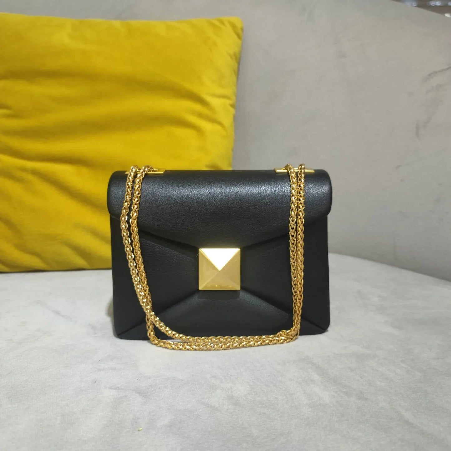 Women's black faux leather envelope crossbody bag with gold rivet hardware and chain strap