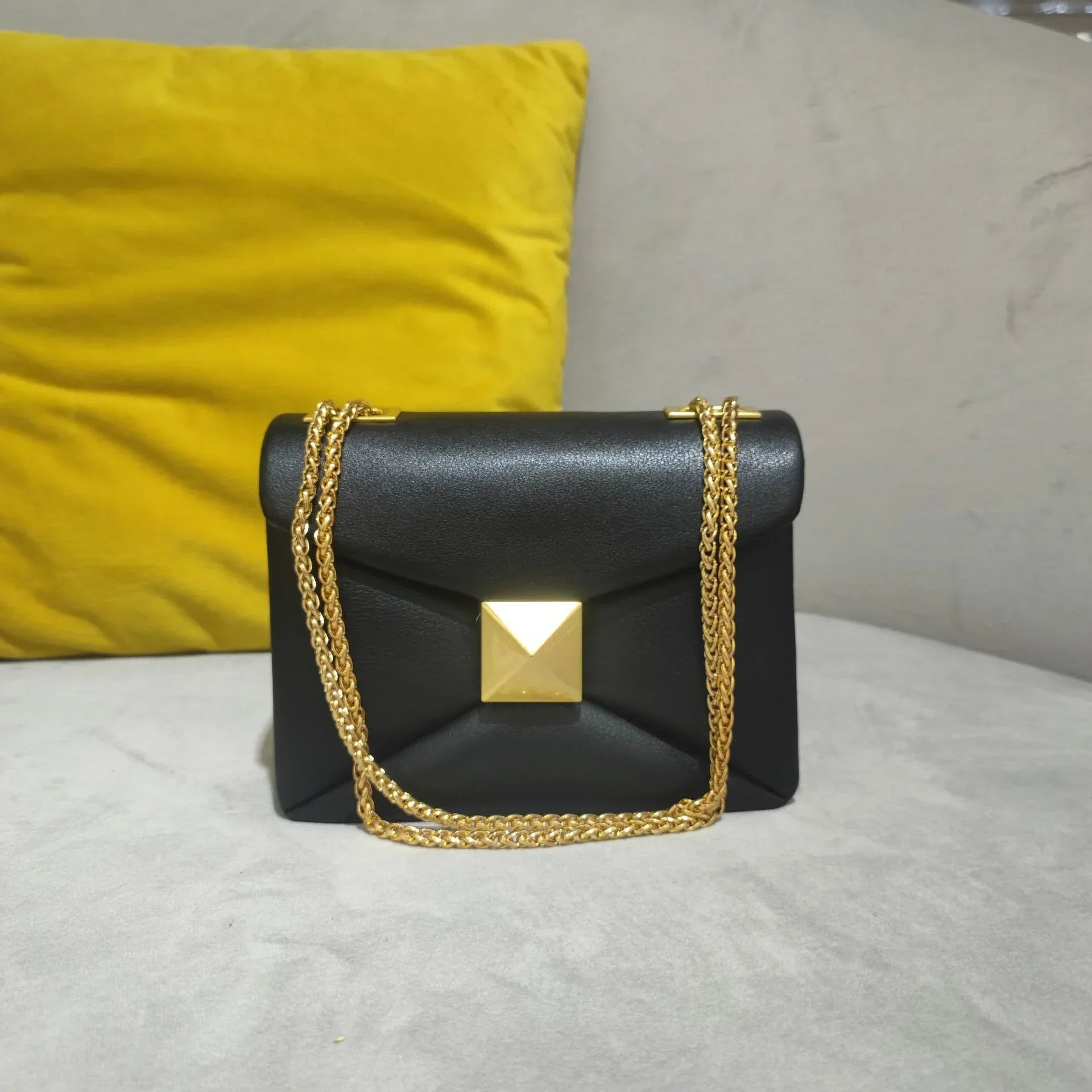 Women's black faux leather envelope crossbody bag with gold rivet hardware and chain strap