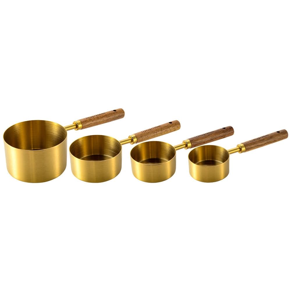 Gold-toned metal measuring cup set with wood handles, engraved markings, elegant kitchen tool