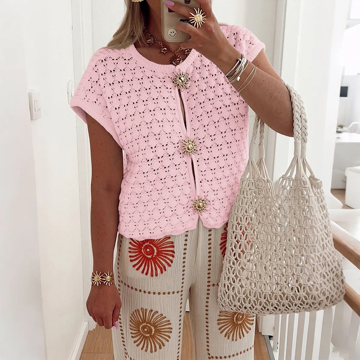 Women's white crochet knit cropped blouse with airy texture and sunburst floral buttons